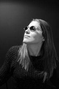 Close-up of woman wearing sunglasses against black background