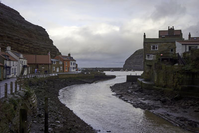 Houses by sea against sky in city