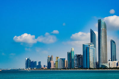 City at waterfront against cloudy sky