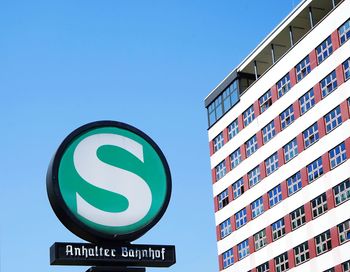 Low angle view of road sign against clear blue sky