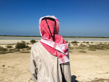 Rear view of qatari arab man on beach against clear sky
