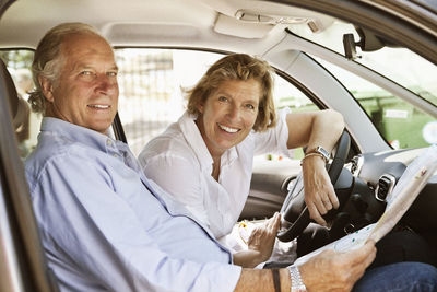 Portrait of couple sitting in car with road map