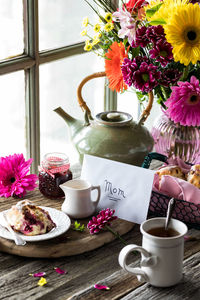Mother's day arrangement of tea and scones with pretty flowers in behind.