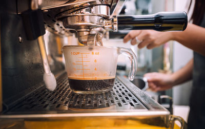 Midsection of barista preparing coffee at cafe