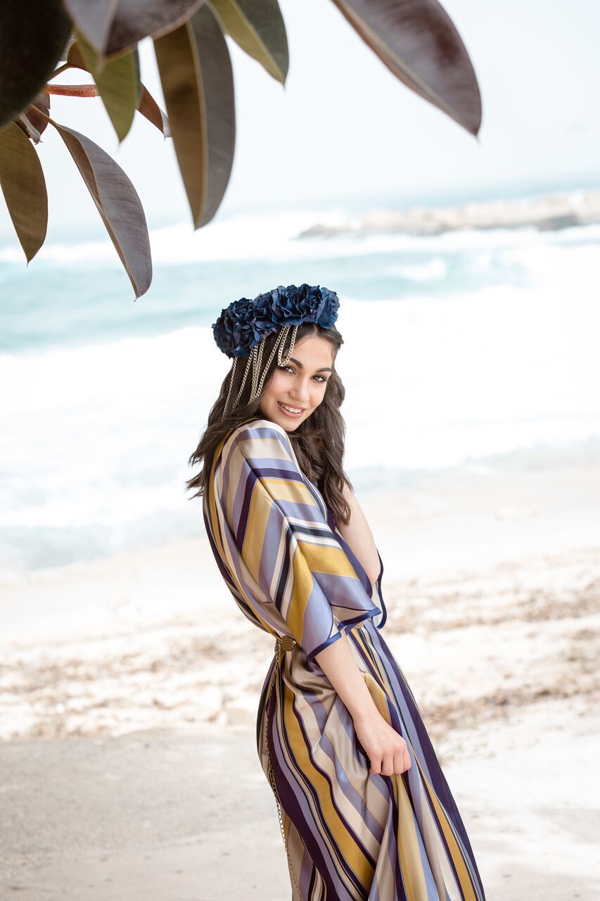 YOUNG WOMAN SMILING WHILE STANDING ON BEACH