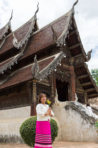 Portrait of woman with bouquet standing outside temple 