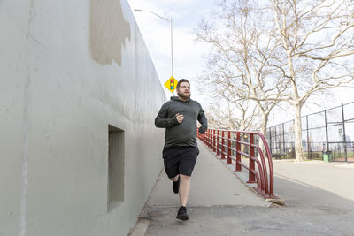 Full length of overweight man jogging in city