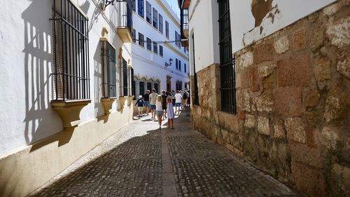 People walking on footpath amidst buildings in city