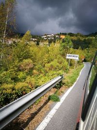 Railway tracks seen through train windshield on field against cloudy sky