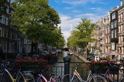 Bicycles by canal amidst buildings in city