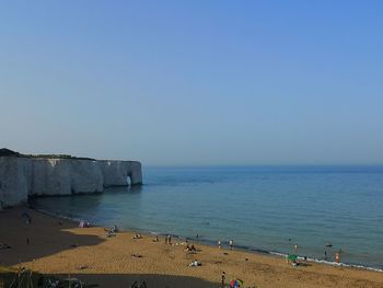 Group of people on beach against clear sky
