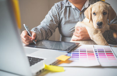 Midsection of man holding dog sitting on table