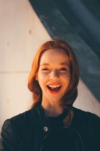 Portrait of happy woman with mouth open against wall