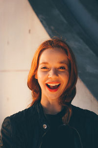 Portrait of smiling young woman against wall