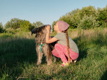 Little girl hugging playing with dog walking spending time together. child with pet in summer meadow