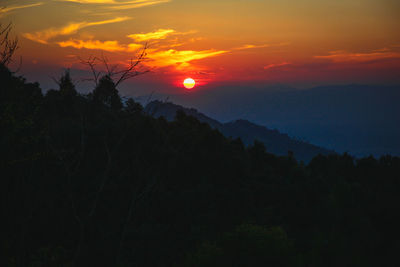 Scenic view of silhouette mountains against orange sky