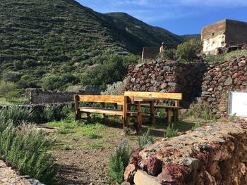 Empty bench on rock against sky