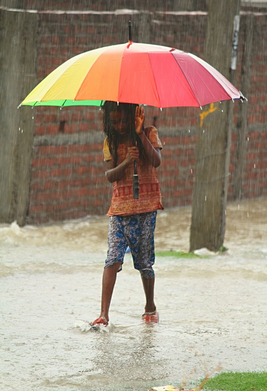 FULL LENGTH PORTRAIT OF HAPPY WOMAN STANDING ON WET SAND