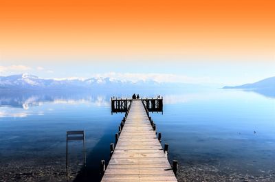 Pier over lake against sky during sunset