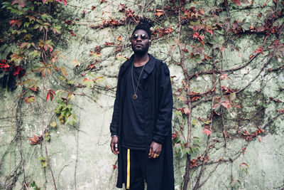 Portrait of young man standing against plants