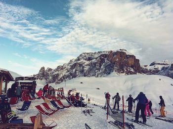 Group of people on snowcapped mountain against sky