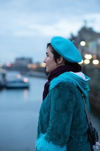 Young woman looking away while standing in city during winter