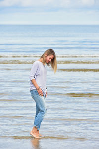 Full length of young woman standing at beach