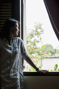 Young woman looking through window