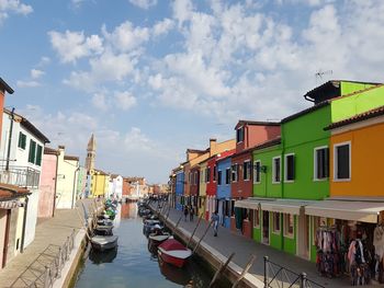 Boats in canal amidst buildings in city against sky