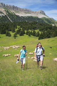 Rear view of people on field against mountains