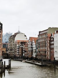 Boats in canal in city against sky