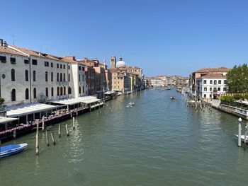 Canal amidst buildings against clear sky