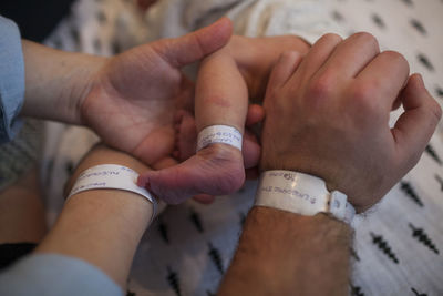 Cropped image of parents and newborn baby with hospital identification bracelets