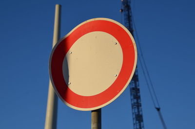 Low angle view of road sign against clear blue sky