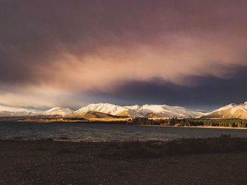 Scenic view of sea by snowcapped mountains against sky