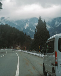 Road by trees against sky