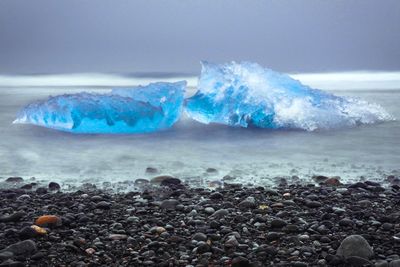 Ice at beach against sky