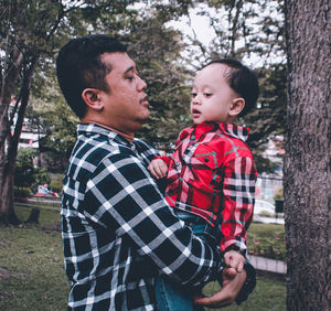 Father and son on tree against plants