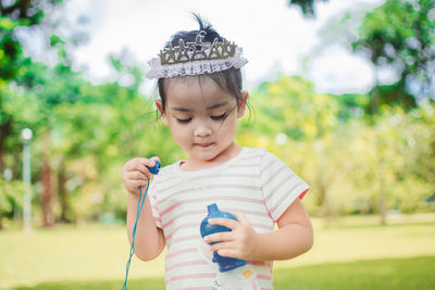 Cute girl blowing bubbles while playing at park