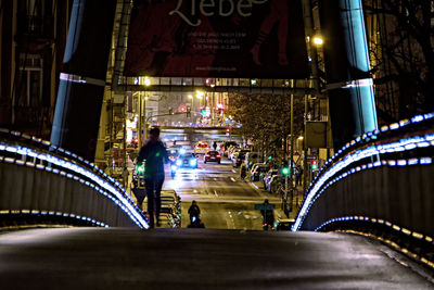 People walking on illuminated road in city at night