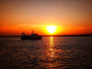 Silhouette boat in sea against sky during sunset