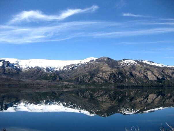 REFLECTION OF MOUNTAIN RANGE IN LAKE AGAINST BLUE SKY