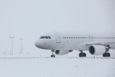 Traffic at airport during snowfall. passenger airplane taxiing to runway for take off on winter day.