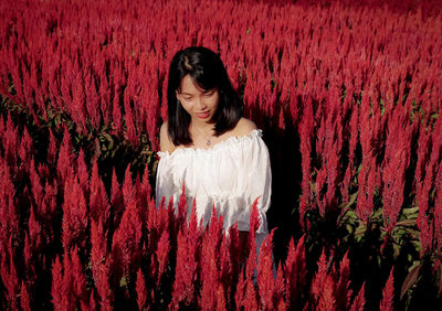 Portrait of beautiful young woman standing against red wall