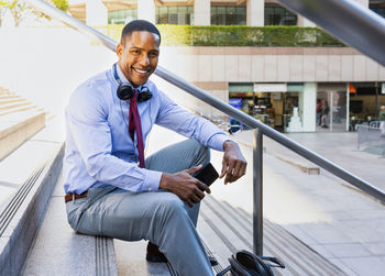 Portrait of young man sitting on escalator