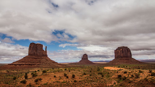 View of rock formations on landscape against cloudy sky