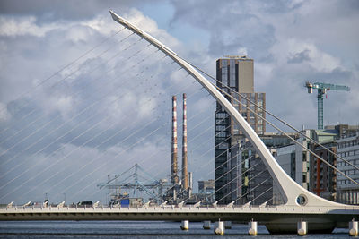 Bridge over river by buildings against sky