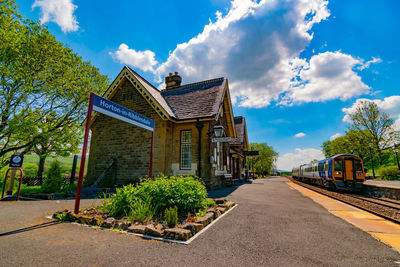 Road by building against blue sky