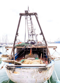 Fishing boat moored at harbor against sky