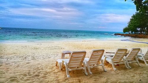 Chairs on beach against sky